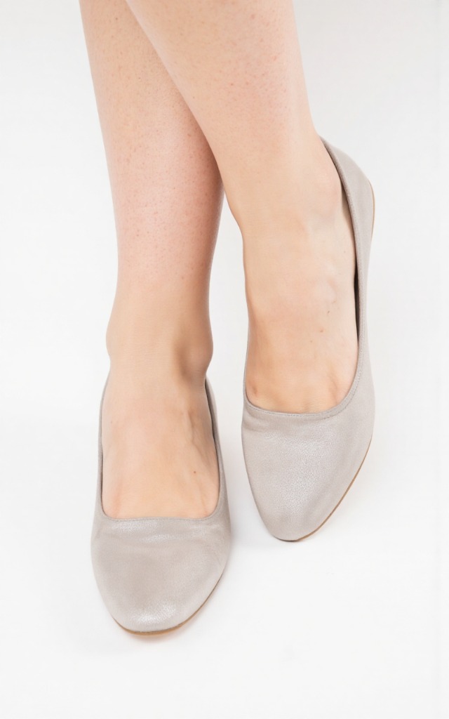 A female model wearing flats, against a white background, with a close   up of the feet